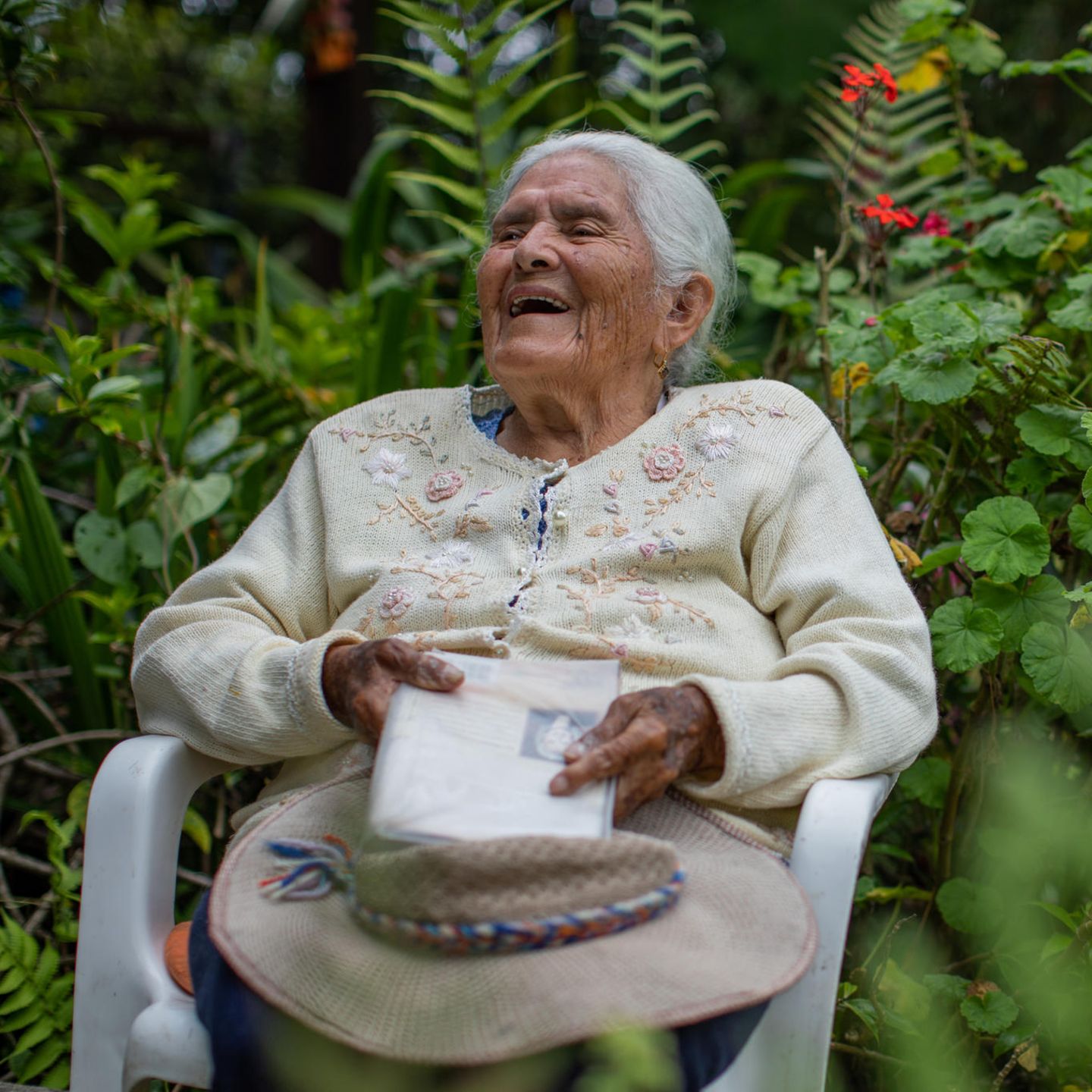 Die 98-jährige Maria Esther Varela sitzt lachend im Garten