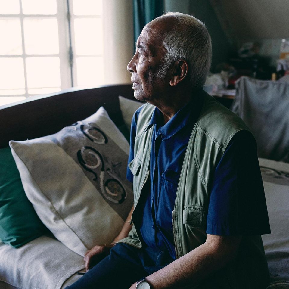 Tonton Jean Paul Randriambelomo sitzt im Schlafzimmer auf seinem Bett