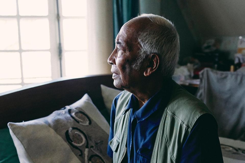 Tonton Jean Paul Randriambelomo sitzt im Schlafzimmer auf seinem Bett