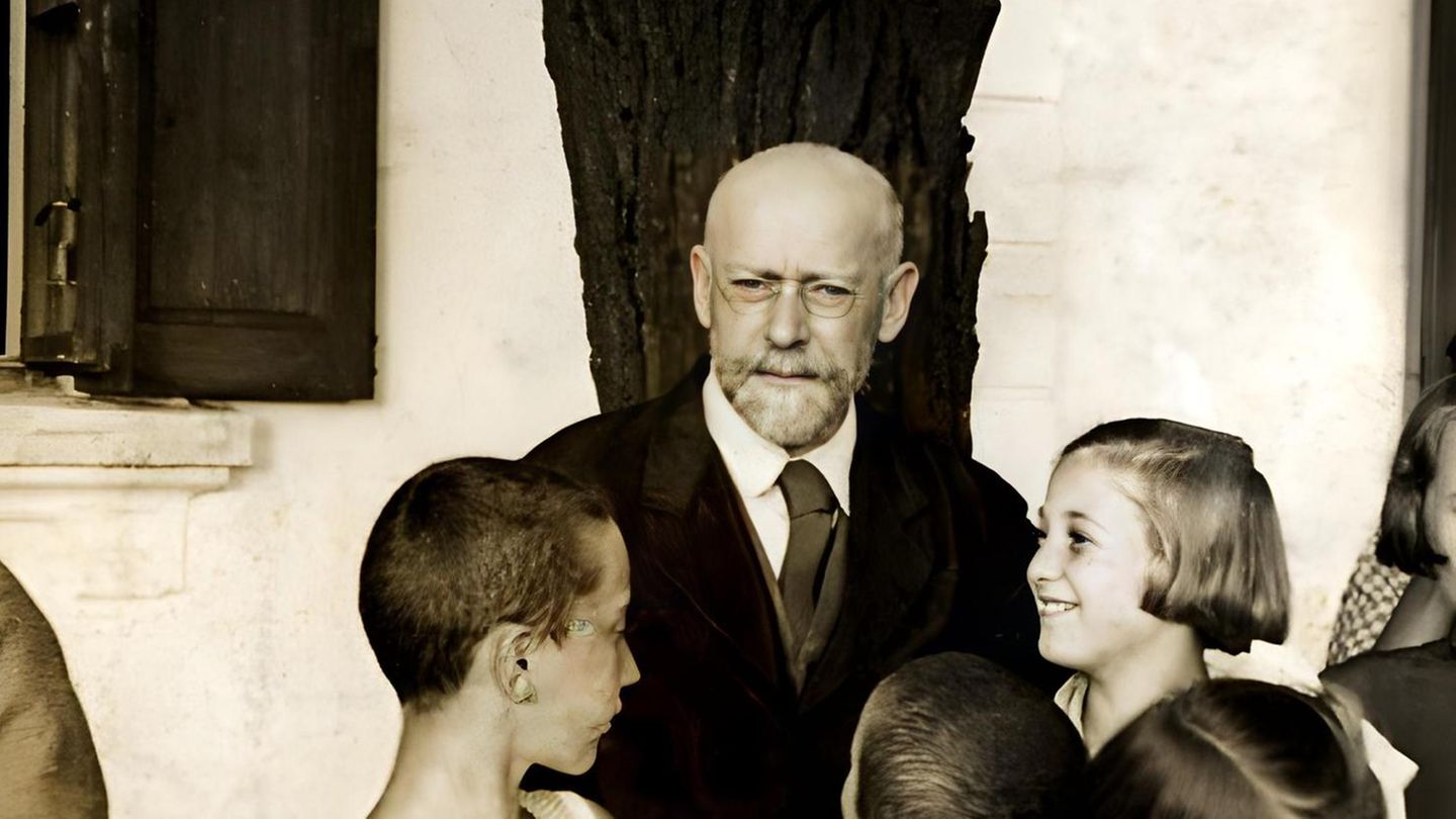 Janusz Korczak, ein älterer Mann mit Bart und Brille, wird von mehreren Kindern umringt Janusz Korczak, ein älterer Mann mit Bart und Brille, wird von mehreren Kindern umringt
