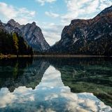 Berge spiegeln sich im See, am Himmel sind ein paar Wolken.