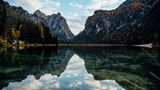 Berge spiegeln sich im See, am Himmel sind ein paar Wolken.