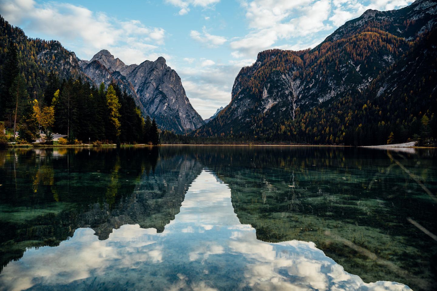 Berge spiegeln sich im See, am Himmel sind ein paar Wolken.