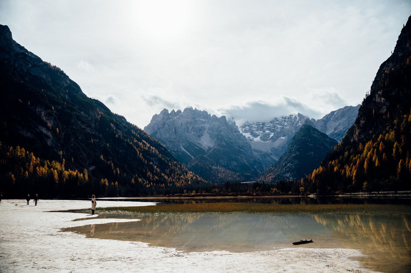 Geröllheimer in den Dolomiten: der Dürrensee  Bewaldete Hänge,  unten ein See mit Kiesbänken. Darauf steht ein Mensch.