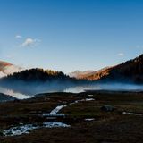 Morgennebel am noch dunklen See, erstes Licht auf den Bergspitzen.