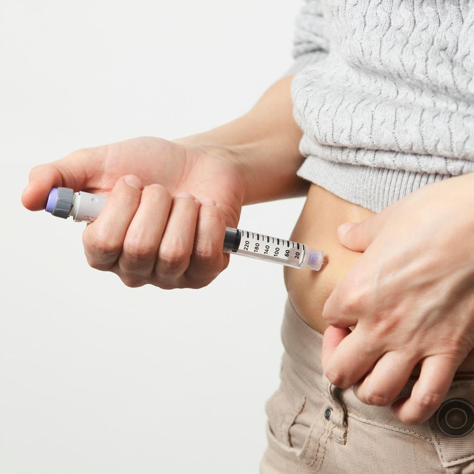 Frau gibt sich Spritze in den Bauch mit Pen