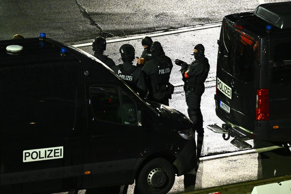 Bundespolizisten stehen zwischen zwei Einsatzfahrzeugen am Hamburger Flughafen