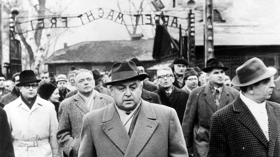 Prozessbeteiligte schreiten durch die Einfahrt zum ehemaligen KZ Auschwitz