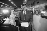 Kennedy mit einer Pappschachtel in der Hand in einem Lebensmittelgeschäft; sw-Foto