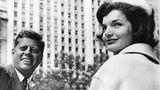 John F. und Jackie Kennedy blicken in einer Häuserschlucht in die Kamera, sw-Foto