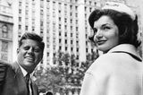 John F. und Jackie Kennedy blicken in einer Häuserschlucht in die Kamera, sw-Foto