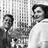 John F. und Jackie Kennedy blicken in einer Häuserschlucht in die Kamera, sw-Foto