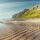 Am Ersfjord-Strand sorgt die Brandung dafür, dass die Wellen auch jenseits des Spülsaumes weitergehen. Umgeben von hohen, steilen Gipfeln entsteht hier eine skandinavische Karibikkulisse. Sie liegt direkt an der beliebten Landschaftsroute 862 auf der Insel Senja