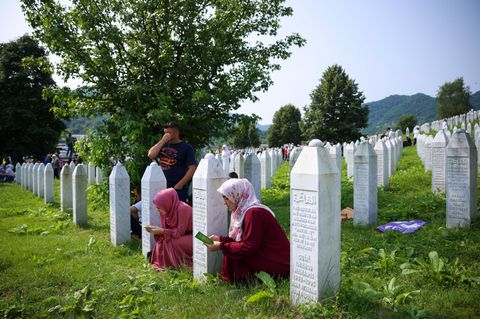 Menschen beten auf einem Friedhof