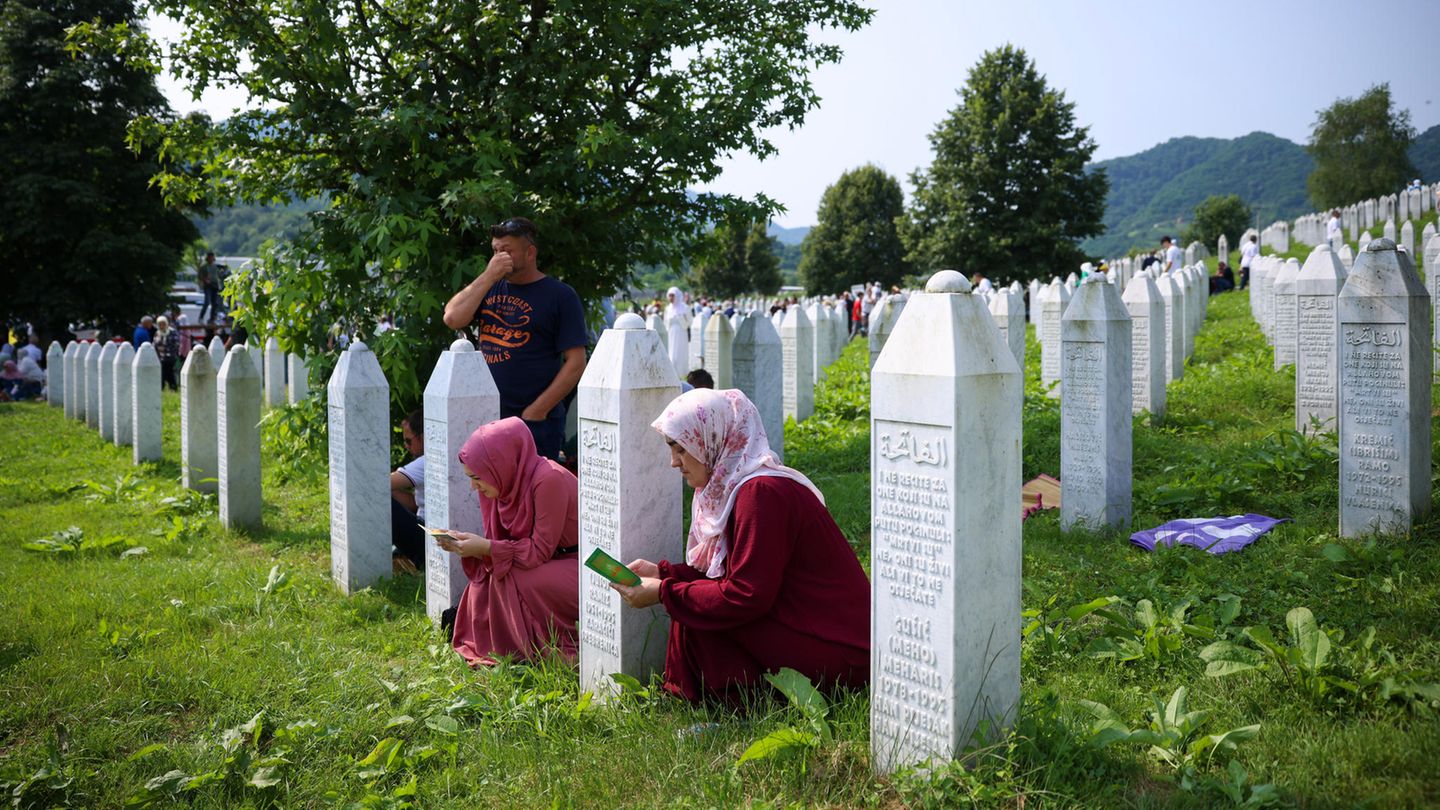 Menschen beten auf einem Friedhof