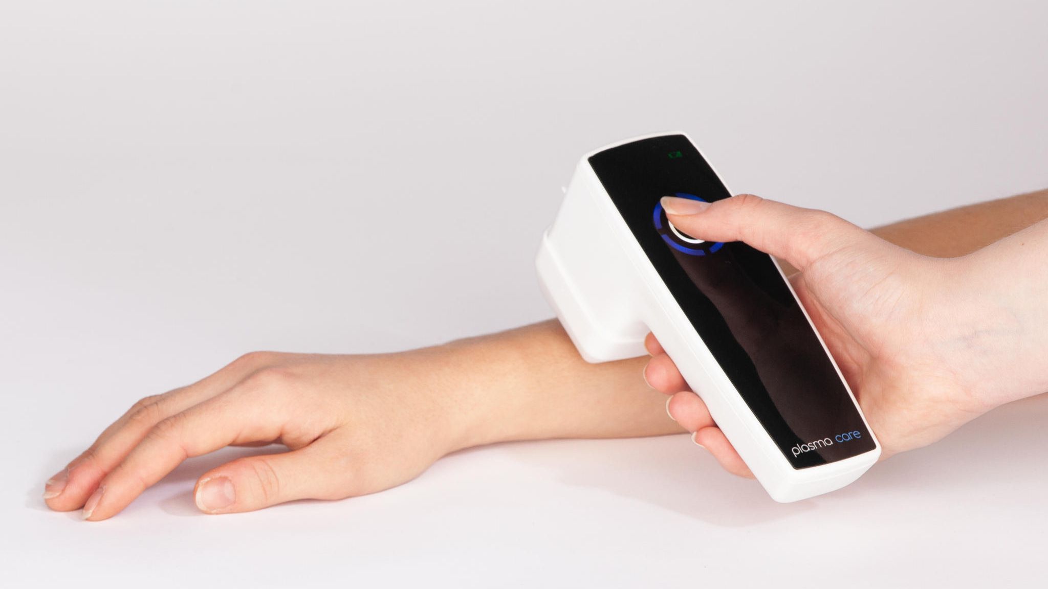 Plasma-Gerät wird auf der Haut eines Arms angewendet  Plasma-Gerät wird auf der Haut eines Arms angewendet