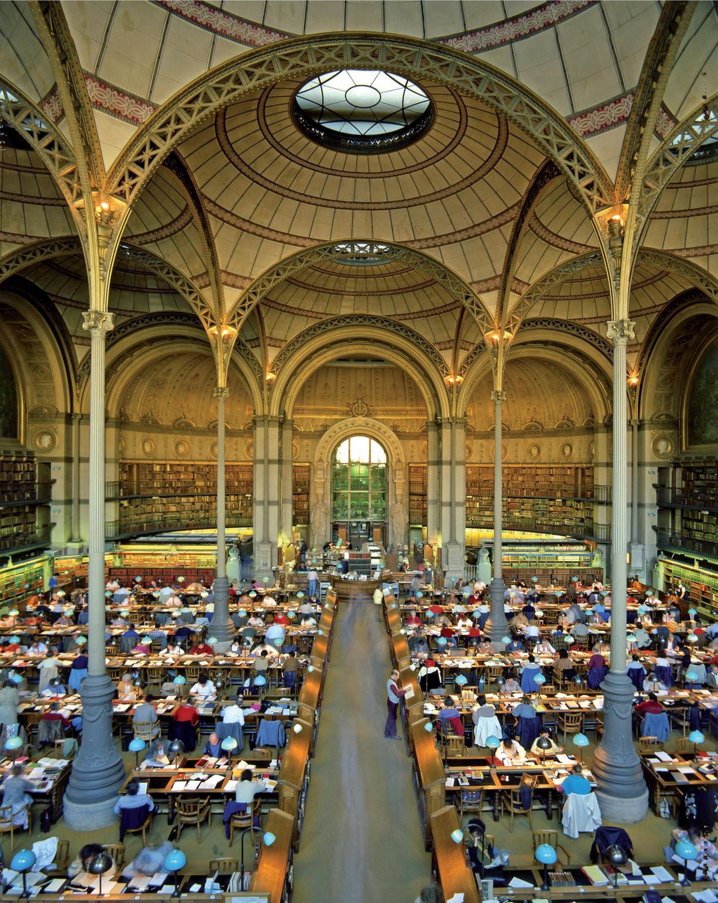Lesetempel: Salle Labrouste in der alten Nationalbibliothek Lange Tische, an denen vielen Menschen lesen, hohe Kuppel auf Säulen.