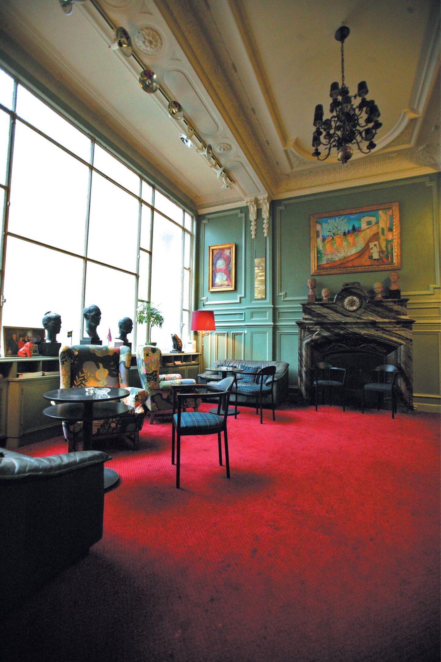 Stühle, Kamin, Büsten in einem sehr hellen, edlen Raum mit großem Fenster.