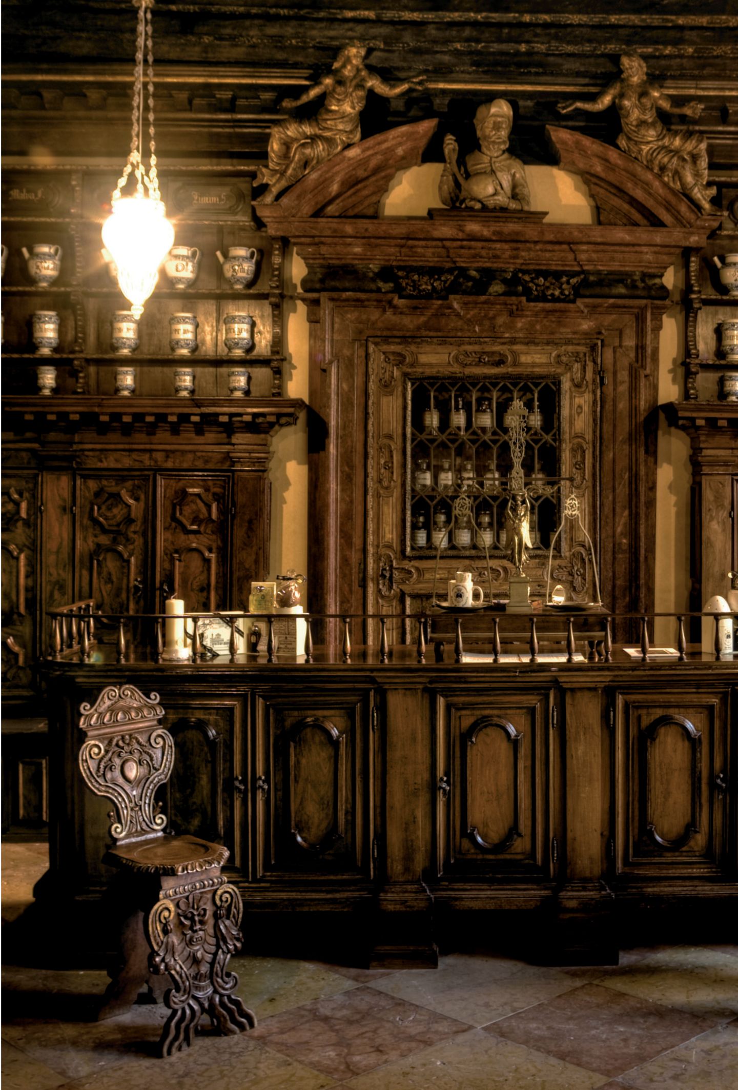 Zaubertrank und giftige Tinkturen: Apotheke All’Ercole d’Oro Verzierte holsvertäfelte Wänder, spärlich beleuchtet, Regale voller Flaschen und Flakons