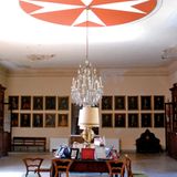 Tisch und Stühle in einem Raum, an der Decke das Malteserkreuz