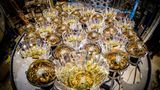 Nach Neutrinos. Was anmutet wie goldglänzende Christbaumkugeln, sind in Wirklichkeit Photodetektoren: Bauteile des EOS-Detektors, der gerade an der University of California Berkeley entsteht. Ab dem kommendem Jahr werden sie auf schwache Lichtblitze lauern, die in einem Tank im Herzen des Detektors aufleuchten und so die Gegenwart von Neutrinos anzeigen sollen. Die superleichten Teilchen entstehen bei Kernreaktionen, etwa in Atomkraftwerken oder im Innern der Sonne. Milliarden von ihnen durchströmen jede Sekunde unbemerkt unseren Körper. Physiker*innen können die Geisterteilchen nur vermessen, indem sie deren Wechselwirkung mit anderen Partikeln auswerten. EOS tut das erstmals mithilfe zweier Techniken, die unterschiedliche Arten von Strahlung messen. Gemeinsam sollen sie unser Bild vom verborgenen Treiben der Neutrinos schärfen.  KW 48  Bildlizenz: CC BY 4.0       