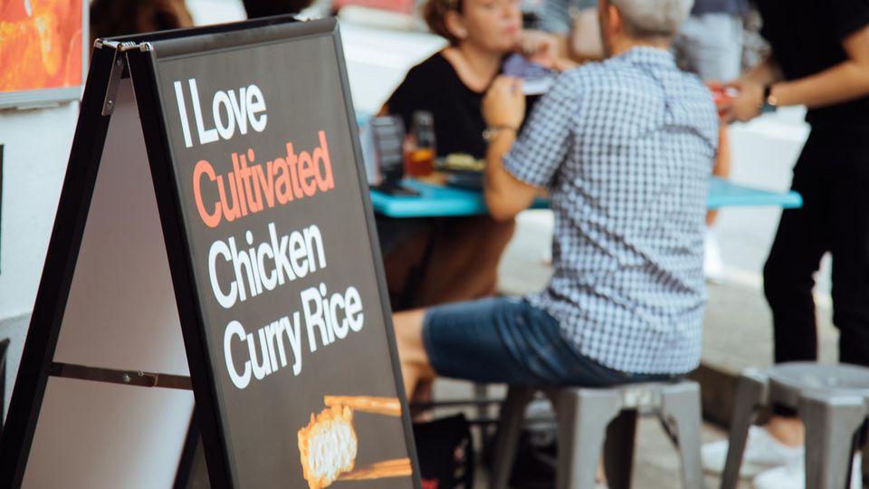 Werbeschild mit kultiviertem Laborfleisch Hühnerzellen vor einem Restaurant Werbeschild mit kultiviertem Laborfleisch Hühnerzellen vor einem Restaurant
