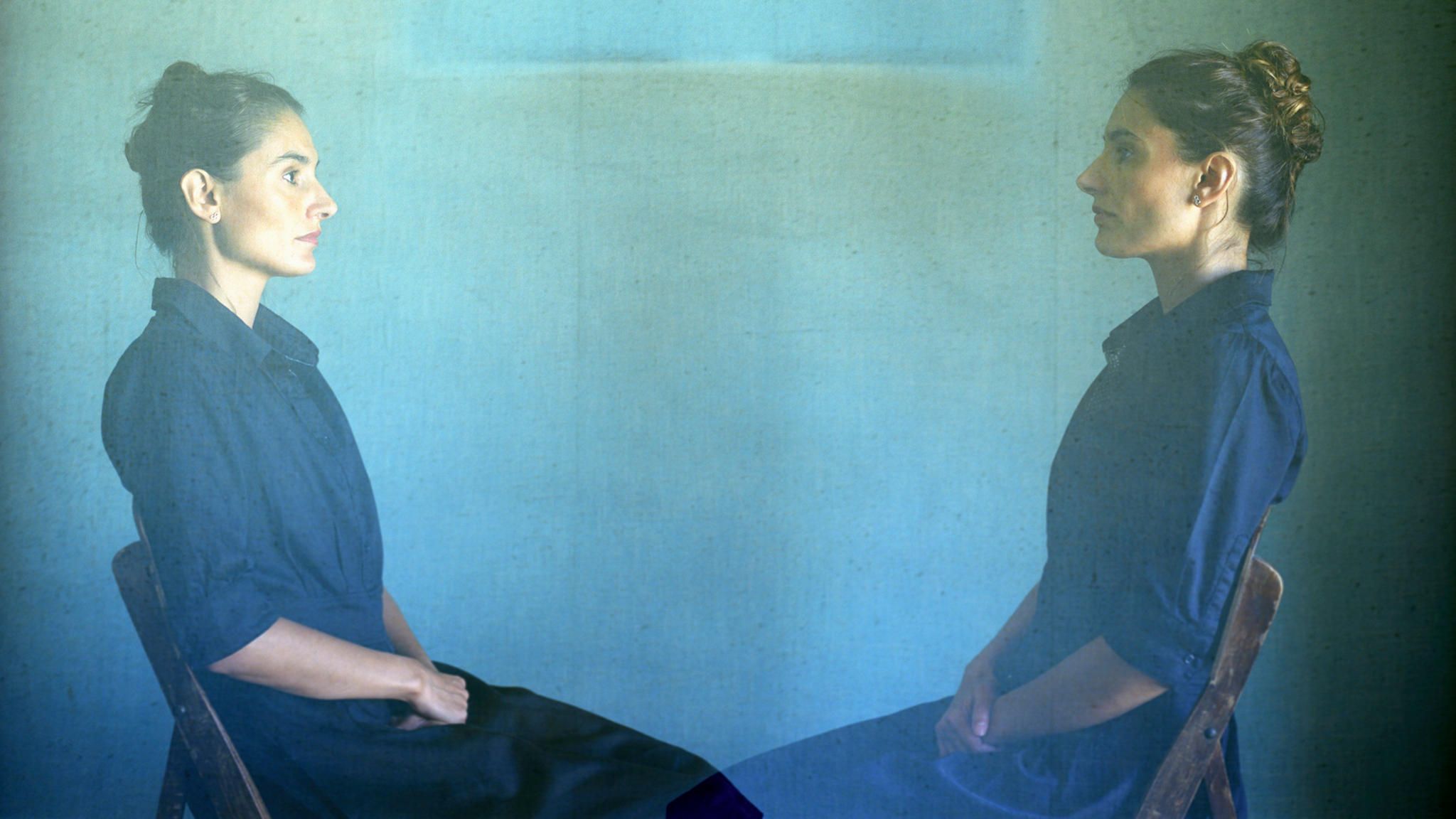 Frau sitzt auf Stuhl und ist doppelt zu sehen  Frau sitzt auf Stuhl und ist doppelt zu sehen