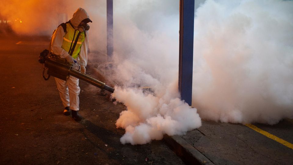 Eine Person sprüht Insektizid in eine Straße