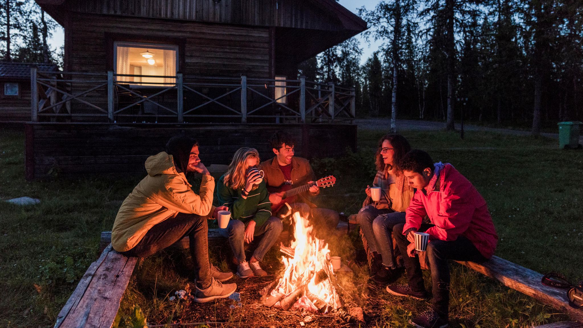 Gruppe von Personen sitzt an einem Lagerfeuer Gruppe von Personen sitzt an einem Lagerfeuer