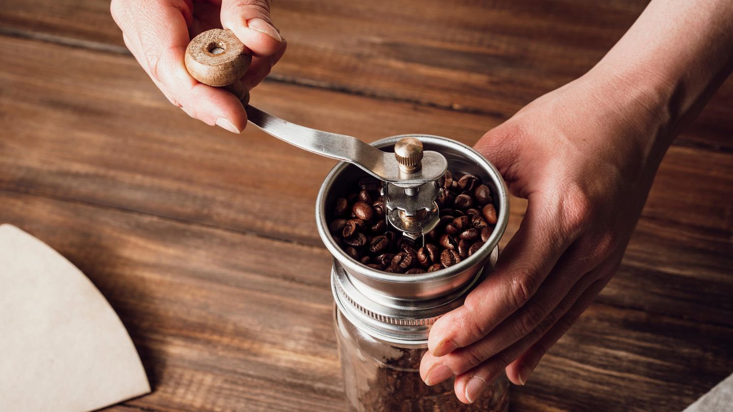 Zwei Hände mahlen Kaffee in einer Mühle