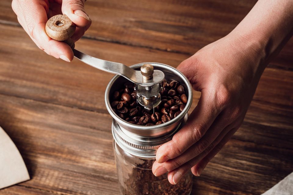 Zwei Hände mahlen Kaffee in einer Mühle  1.4993