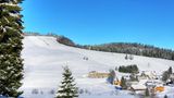 Skipiste an einem sonnigen Tag mit Hütten am unteren Ende
