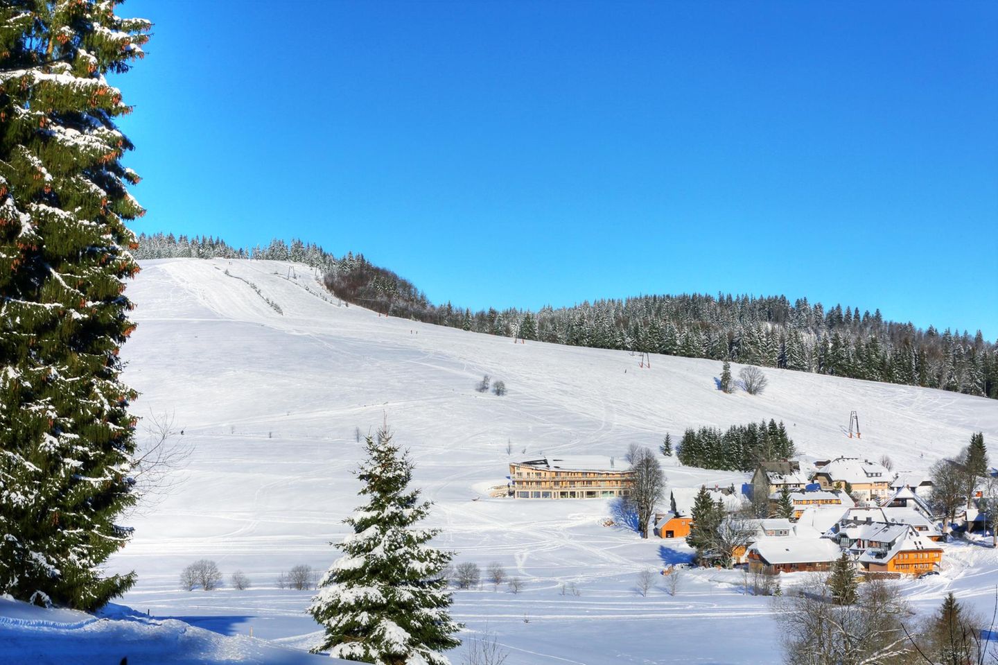 Liegestühle an der Piste: Herrenschwand, Schwarzwald Skipiste an einem sonnigen Tag mit Hütten am unteren Ende