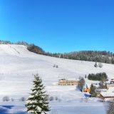 Skipiste an einem sonnigen Tag mit Hütten am unteren Ende