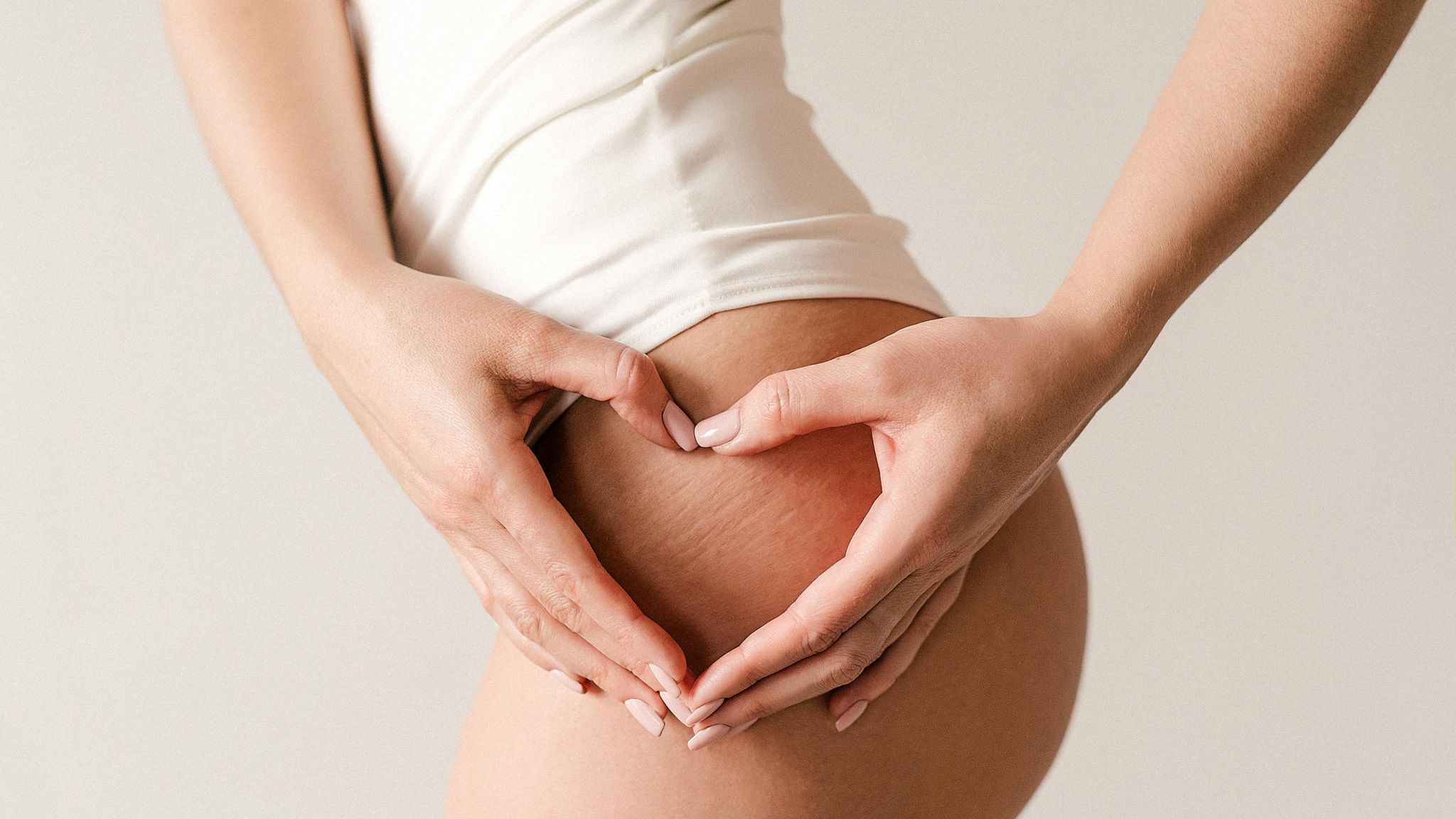 Eine Frau zeigt mit ihren Händen ein Herz auf ihrem Oberschenkel