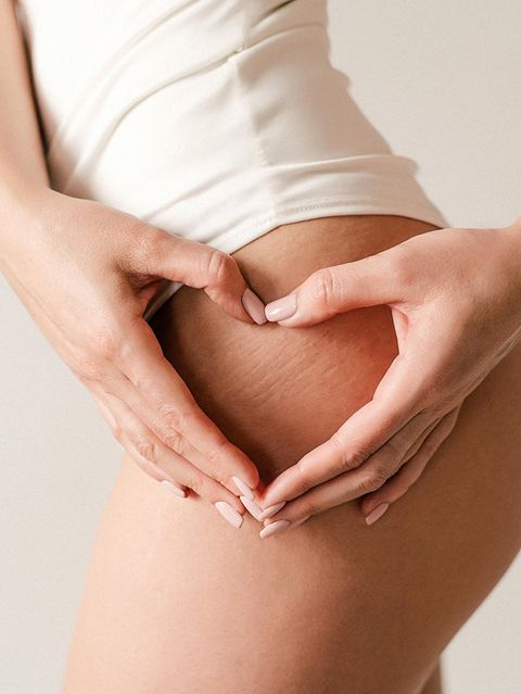 Eine Frau zeigt mit ihren Händen ein Herz auf ihrem Oberschenkel