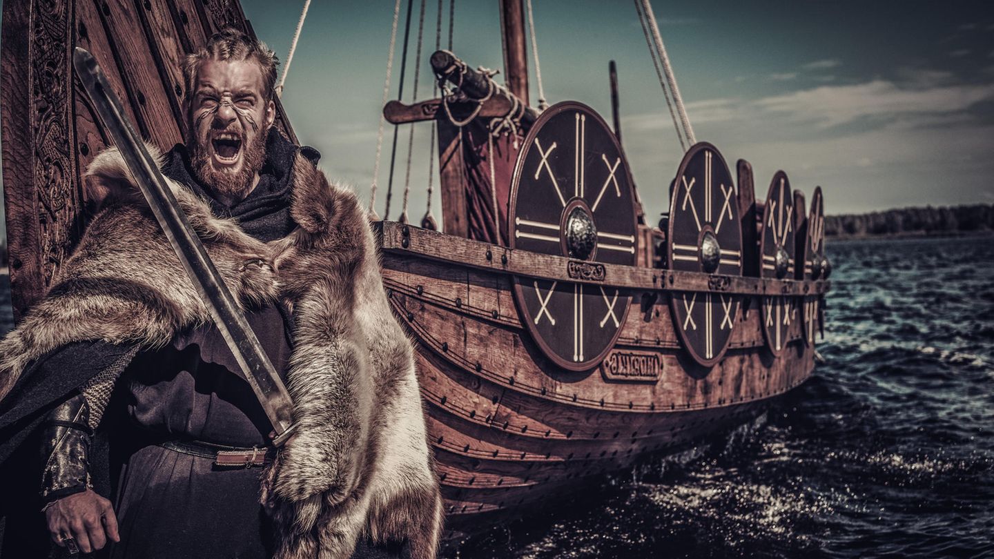 Ein bärtiger Wikinger mit Fellumhang steht vor einem Schiff: schreiend Ein bärtiger Wikinger mit Fellumhang steht vor einem Schiff: schreiend