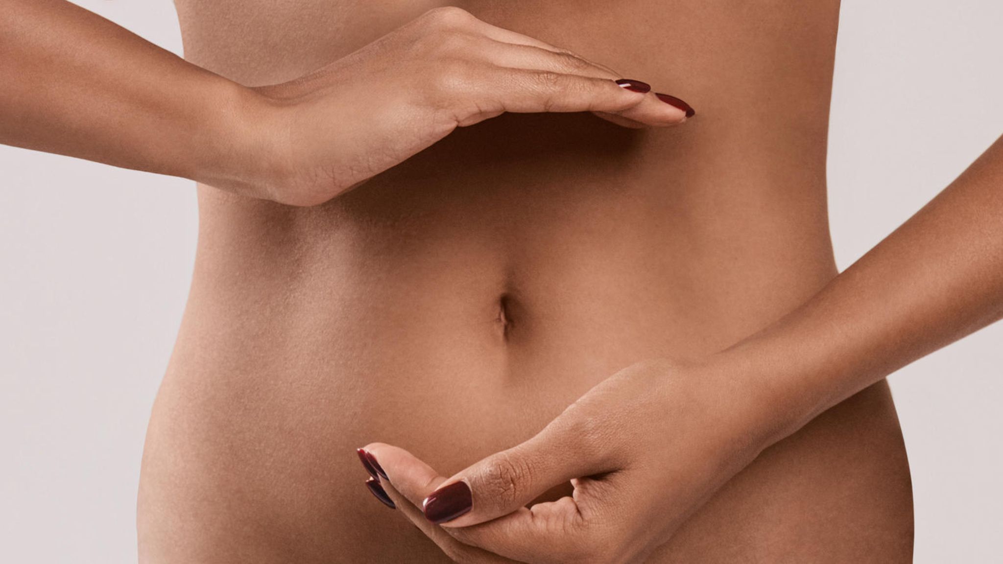 Schlanke Frau mit Händen über dem Bauch