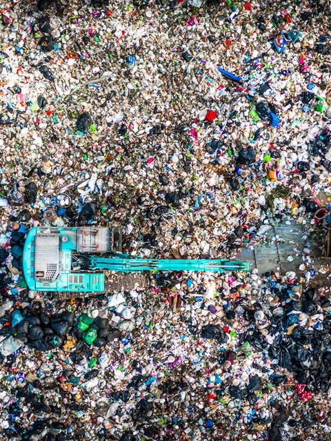Müllkippe mit Bagger und Raupe, der Boden ist bedeckt mit (Verpackungs-)müll