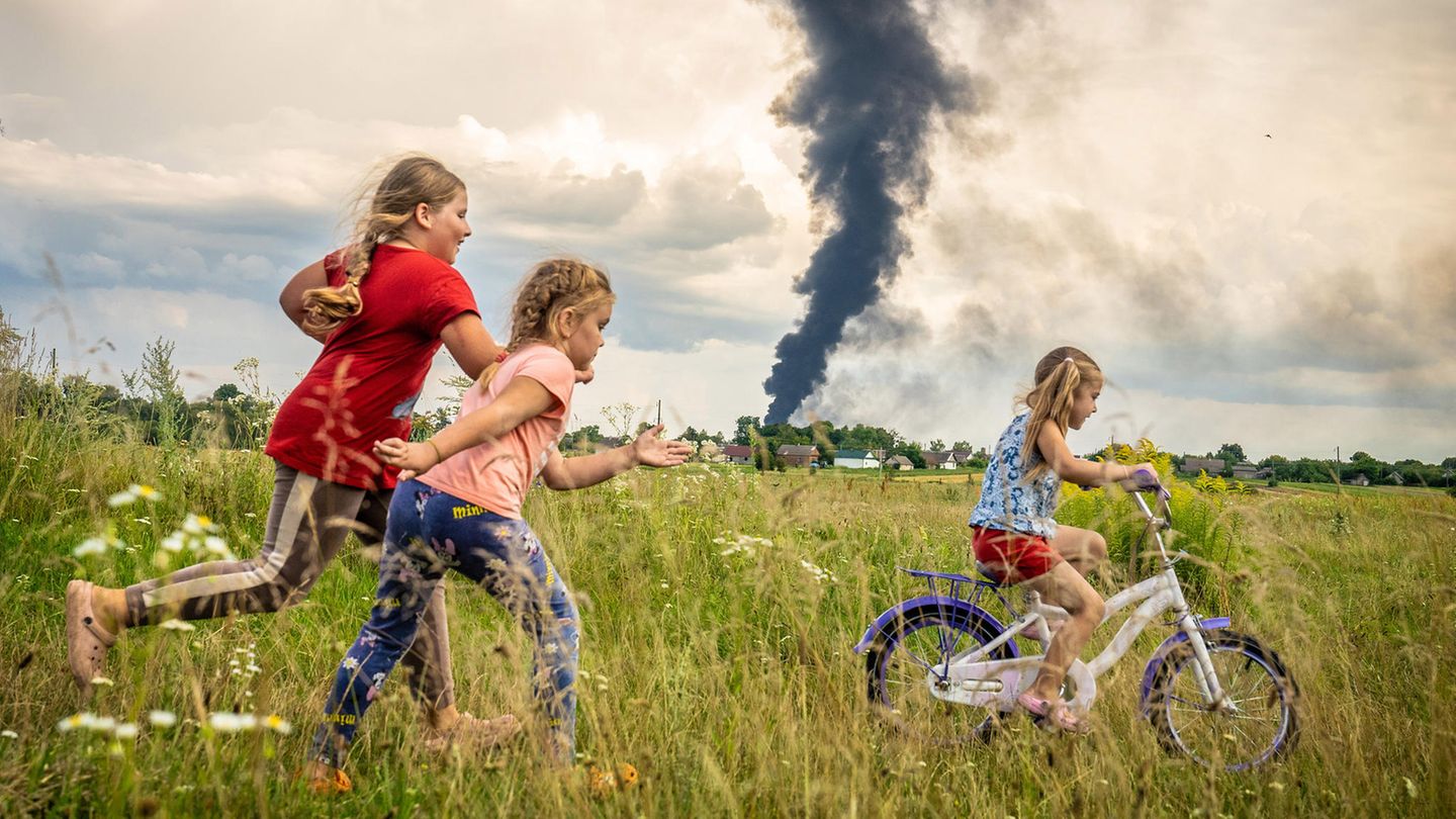 Das Unicef-Foto des Jahres rückt kindliche Unbeschwertheit inmitten des russischen Angriffskriegs gegen die Ukraine in den Mittelpunkt. Auf dem Siegerbild des polnischen Fotografen Patryk Jaracz sind drei Mädchen auf einer Wiese in der Westukraine zu sehen. Eines davon lernt das Fahrradfahren, während im Hintergrund eine schwarze Rauchwolke von einem Öllager aufsteigt. Die Siegerfotos wurden am Donnerstag in Berlin präsentiert.  Jaracz habe eine "sehr bewegende Szene mit einem sehr beklemmenden Kontrast festgehalten", sagte Unicef-Schirmherrin Elke Büdenbender, die Frau des Bundespräsidenten Frank-Walter Steinmeier. "Der Krieg hängt wie eine richtig dunkle Wolke über dem Alltag der Kinder." Trotzdem zeige es auch Hoffnung.