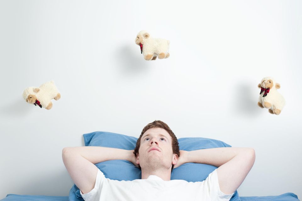 Mann liegt wach im Bett und zählt Schäfchen 1.6