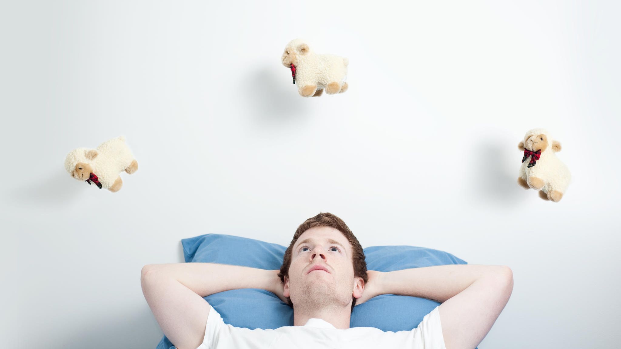 Mann liegt wach im Bett und zählt Schäfchen Mann liegt wach im Bett und zählt Schäfchen