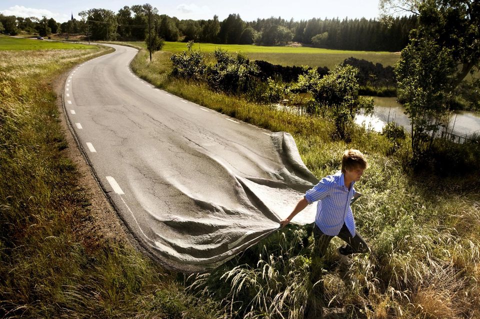 Ein Mann zieht eine Straße über eine Wiese. Illustration von Erik Johansson  1.561