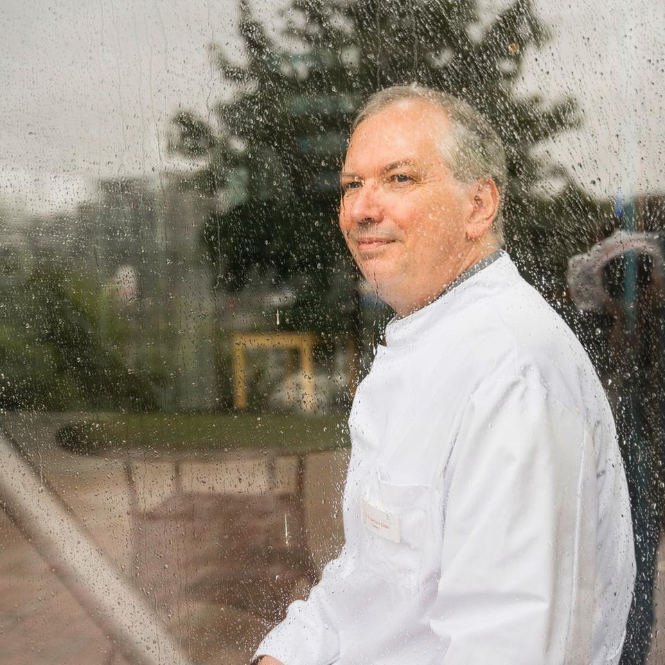 Hartmut Göbel sitzt lächelnd hinter einer verregneten Scheibe seiner Klinik