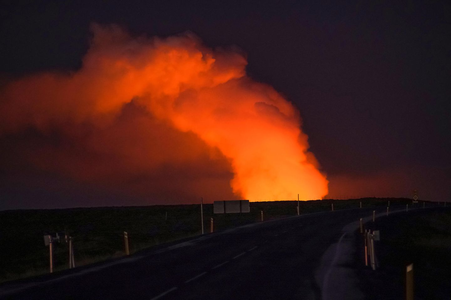 Weitgehend ruhig am Montagmorgen Straße im Dunkeln mit Feuerwolke beim Vulkanausbruch auf Island im Januar 2024