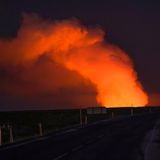 Straße im Dunkeln mit Feuerwolke beim Vulkanausbruch auf Island im Januar 2024