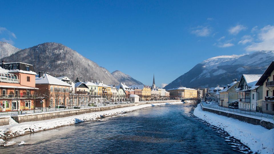 Vorne der Fluss, rechts und links die kleinen Häuser der kleinen Stadt, es liegt Schnee auf den Hügeln im Umland.