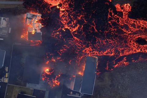 Brennende Häuser werden von Lava umflossen