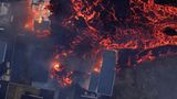 Brennende Häuser werden von Lava umflossen