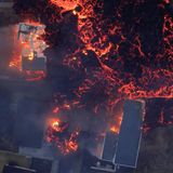 Brennende Häuser werden von Lava umflossen